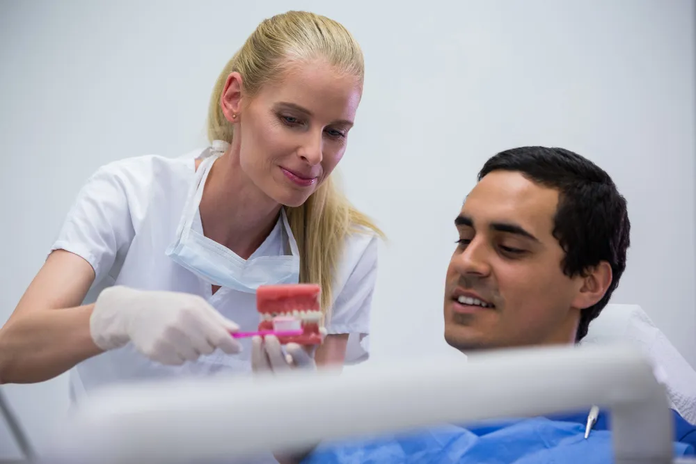 Dental team member using a teeth model to explain tooth replacement to a patient